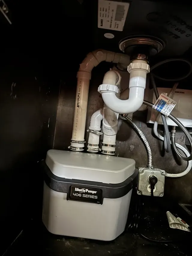 A Liberty sink ejector pump installed under a sink with new drain piping