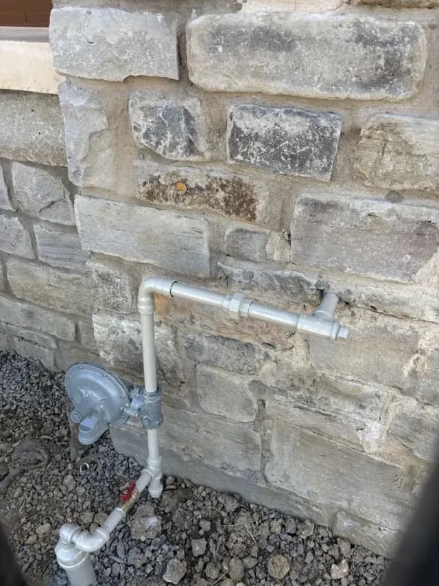 New gas regulator and gas piping installed on the stone wall of a home