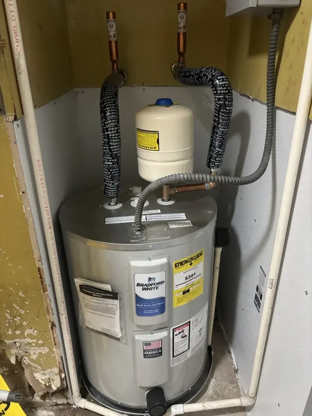 A new electric water heater with expansion tank installed in a closet
