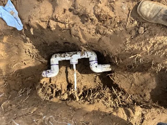 Underground water line dug out and repaired with new white PVC fittings